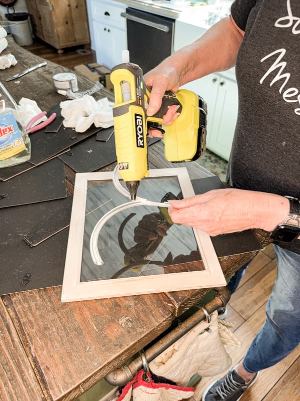 Attach architectural arches cut from the garden fence to the glass on picture frames with hot glue to make a DIY Glass Terrarium.