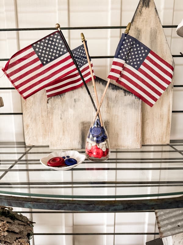 Vase with red, white and blue buttons with American flags on shelf