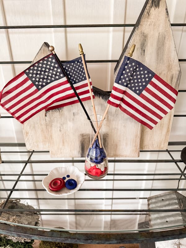 Vase with red, white and blue buttons with American flags on shelf