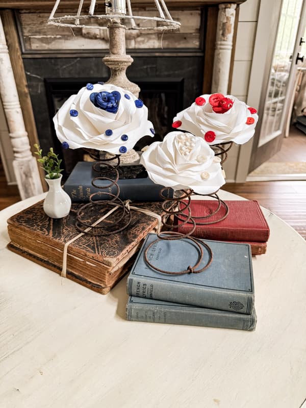 DIY Patriotic Paper roses with vintage buttons on rusty old mattress spring with vintage red and blue books. DIY button crafts