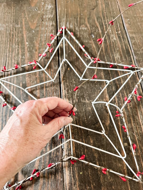 Wrap red beaded garland around  frame for a coastal wreath with Dollar tree supplies. 