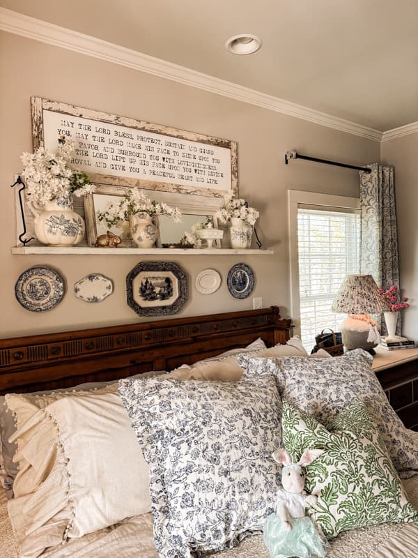 view of bed with pillows and shelf with white azaleas