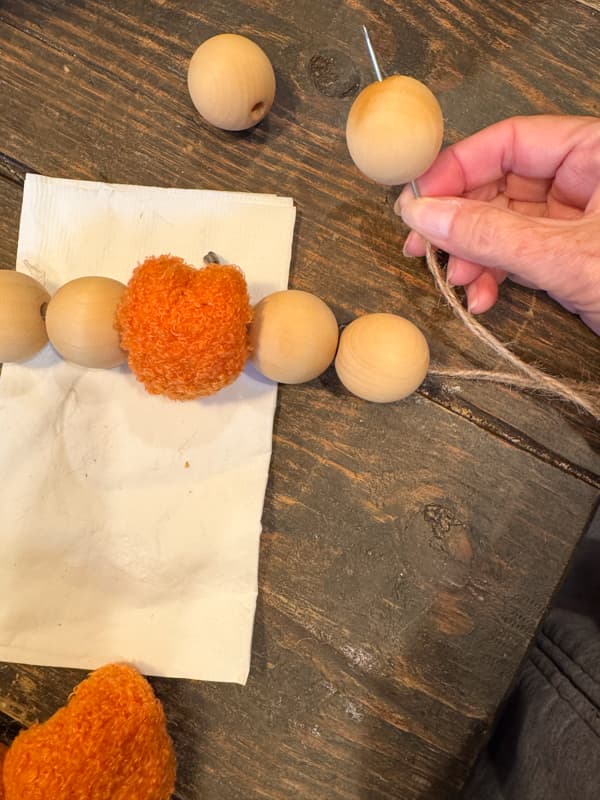 thread the beads and pumpkins onto the twine via the needle