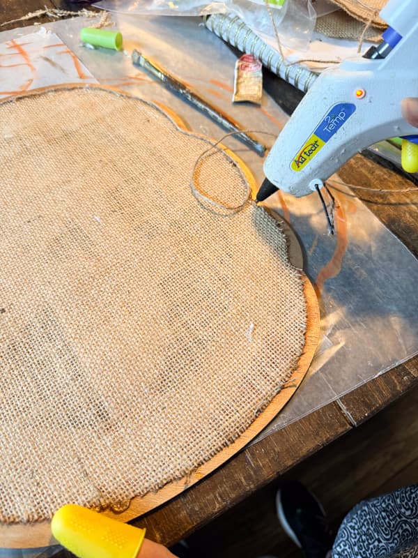 add hot glue to attach jute twine to burlap edge