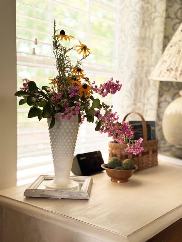 side table with milk glass vase filled with garden flowers.