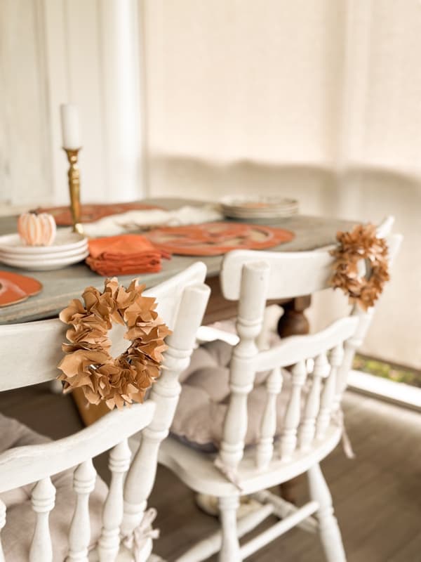 two mini faux corn husk wreaths on backs of chairs