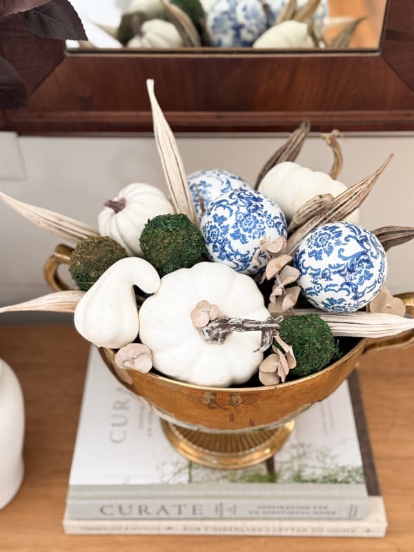brass bowl with pumpkins, blue & white balls, & moss spheres.  