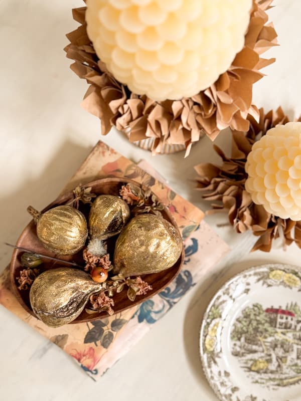 gold figs in wooden bowl with pinecone candles
