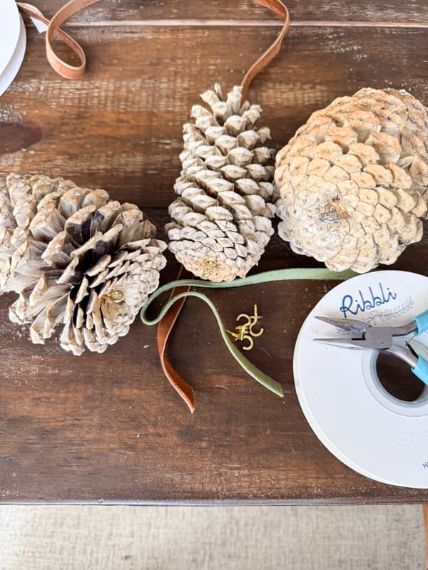 add ribbon and eye hooks to bleached pinecones