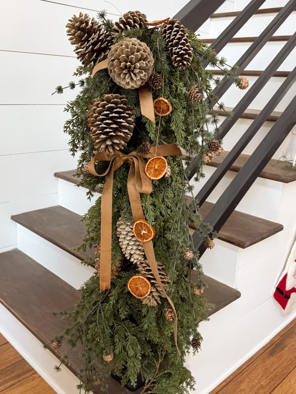 Iron banister with greenery and pinecones at the end