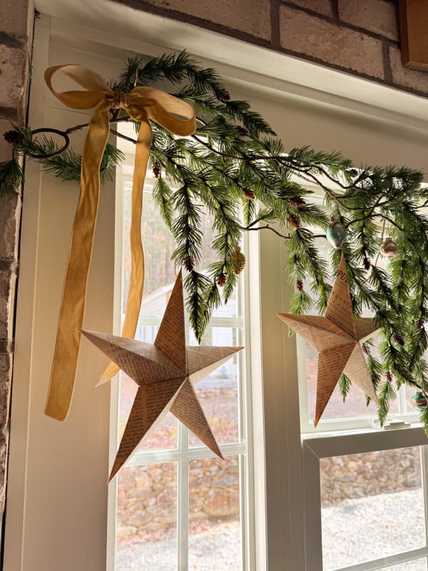 old book page Christmas stars hanging with garland over window