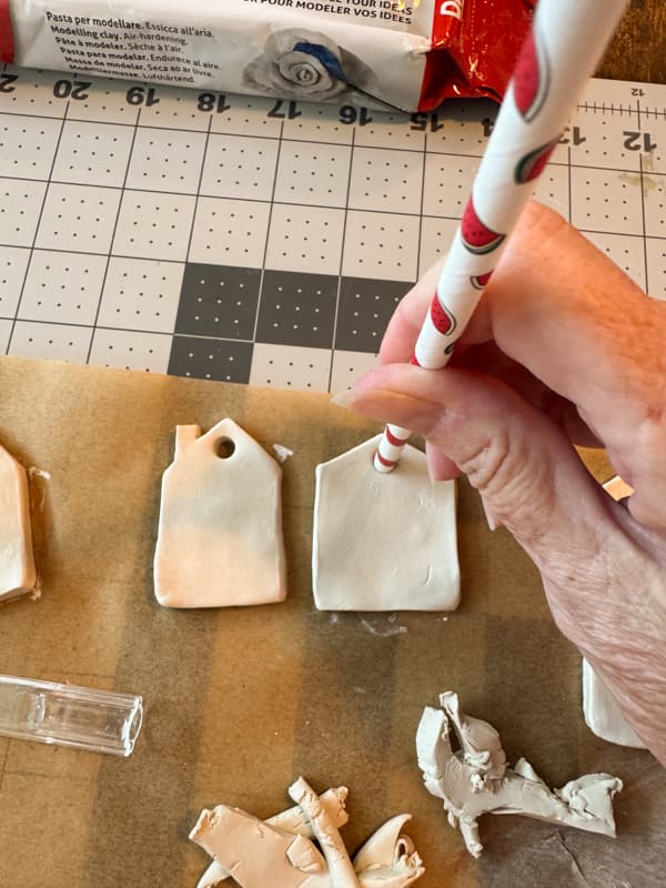 punch holes in gingerbread house ornaments with straw. 
