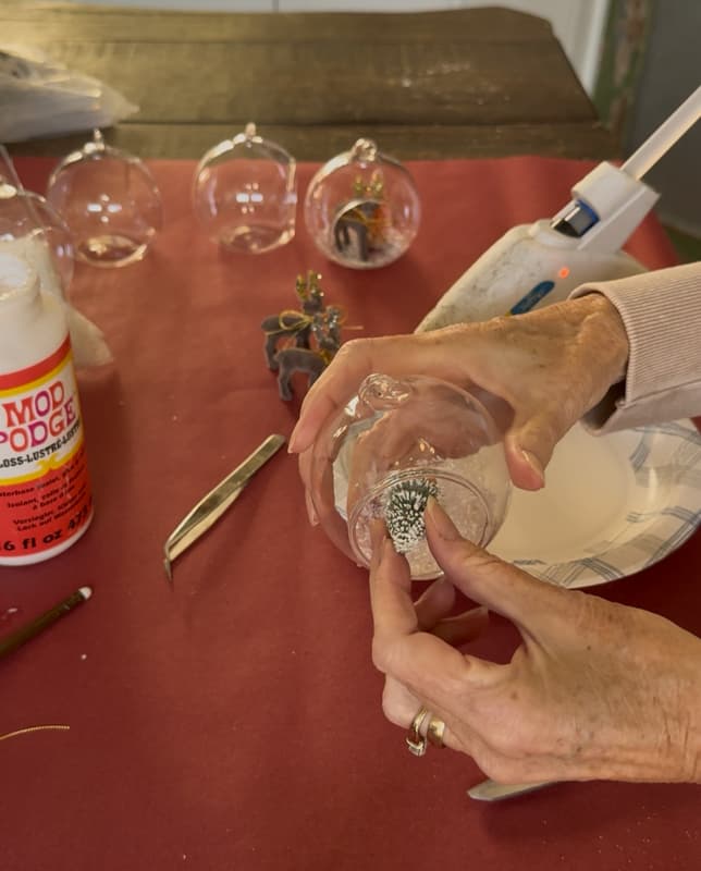 add mini bottle brush tree to inside of glass globe