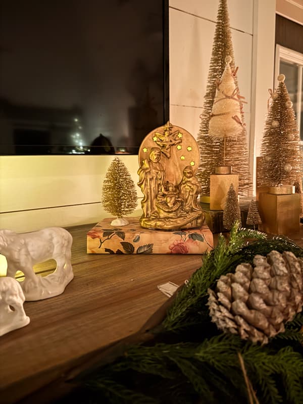 tea light nativity scene with bottle brush trees on mantel in candle light