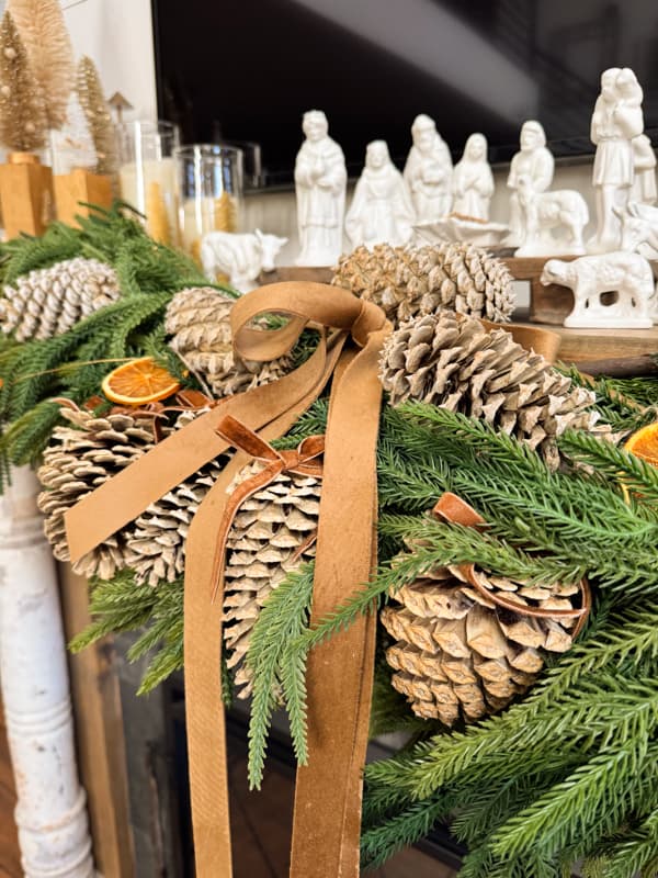 bleached pinecones with velvet brown ribbon on mantel garland.