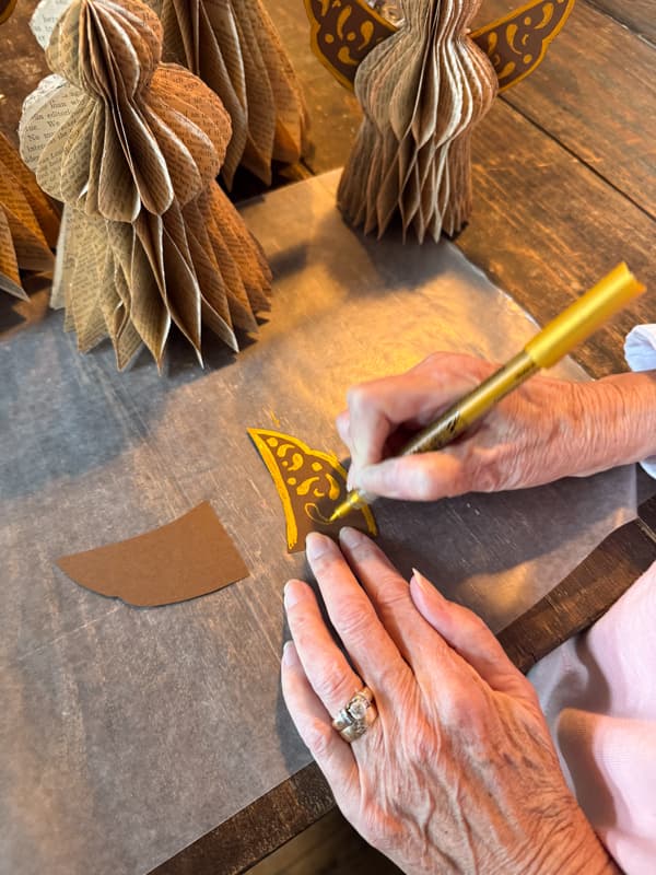 draw designs on the angel wing with gold glitter pen