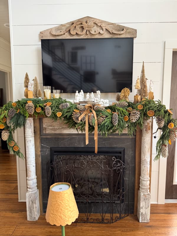 full Christmas mantel with pinecones & orange slices, bottle brush trees and nativities scenes.