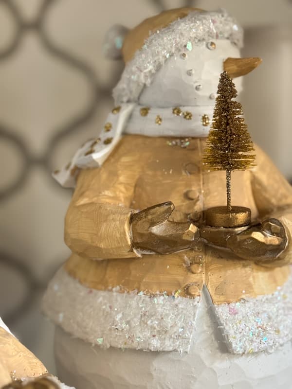 close up of snowman with bottle brush tree