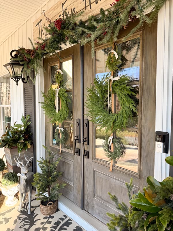 trio of wreaths on french doors with garland above