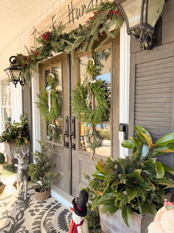 Planters and reindeer by front doors with wreath trios.
