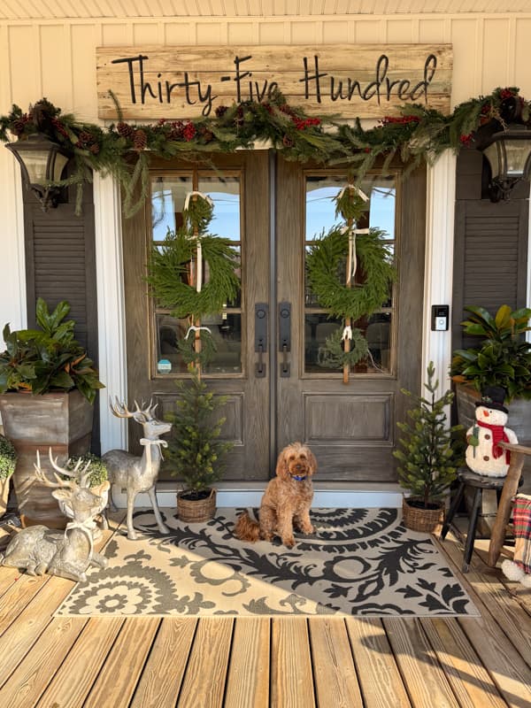 Rudy at the front doors decorated with wreath and garland for Christmas