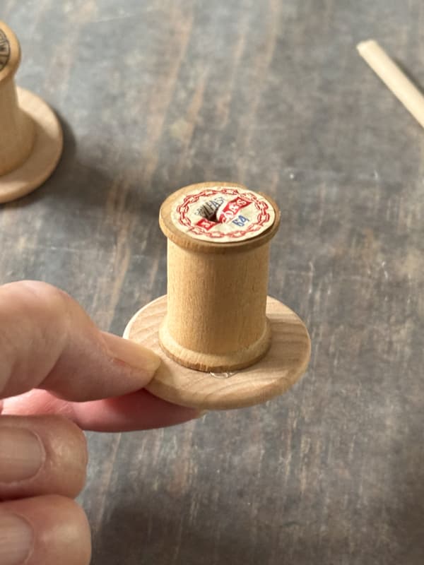 attach wooden thread spool to wood washer with hot glue