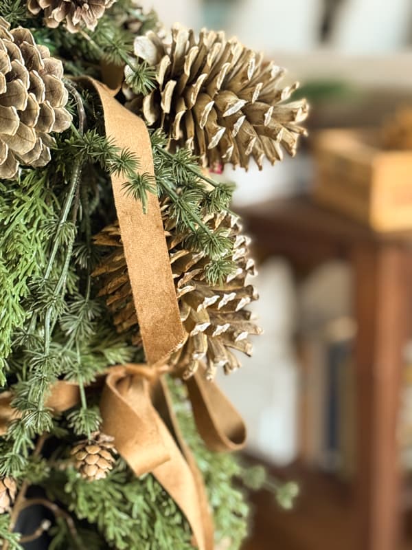 bleached pinecone and greenery arrangement on banister