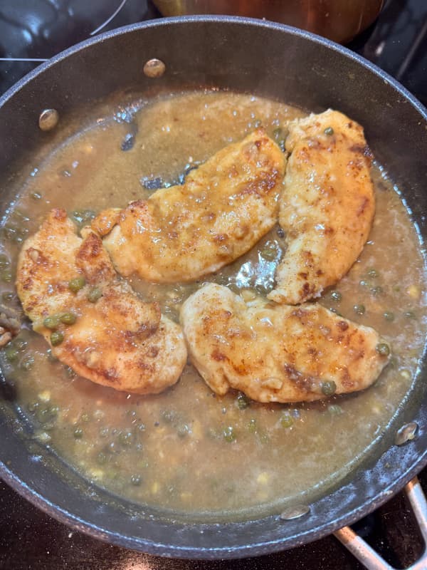 Chicken piccata sauce in skillet with cooked chicken