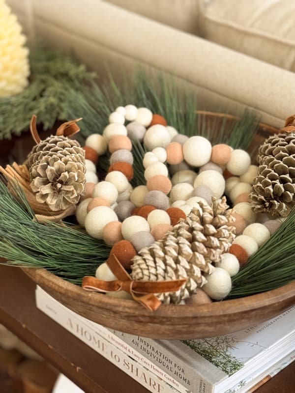 DIY felt ball garland in bowl with greenery and bleached pinecones