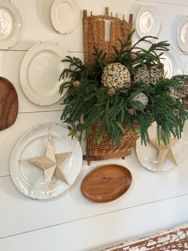 Dining room plate gallery wall with gathering basket filled with greenery and pinecones.  
