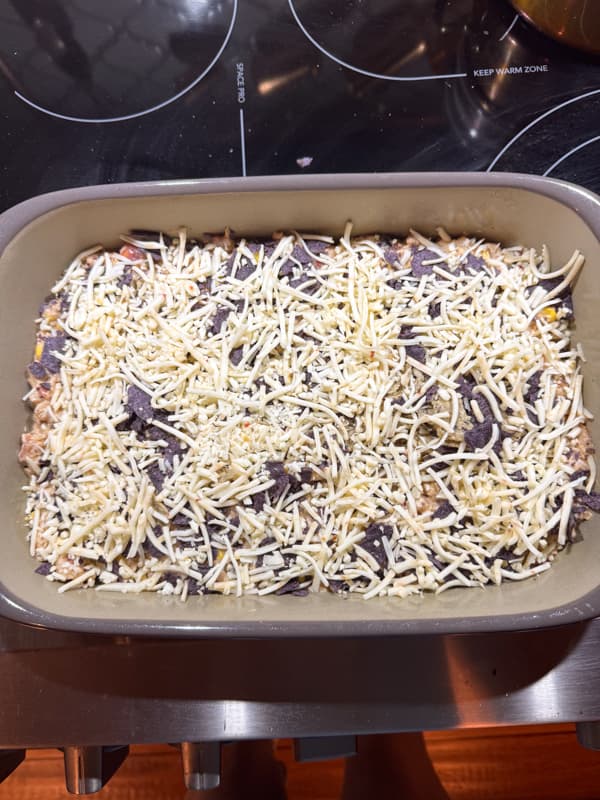 Layering Mexican Chicken Casserole with tortilla chips and cheese