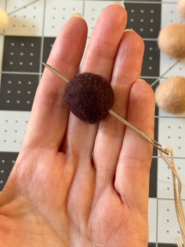 Run needle through the center of the felt balls