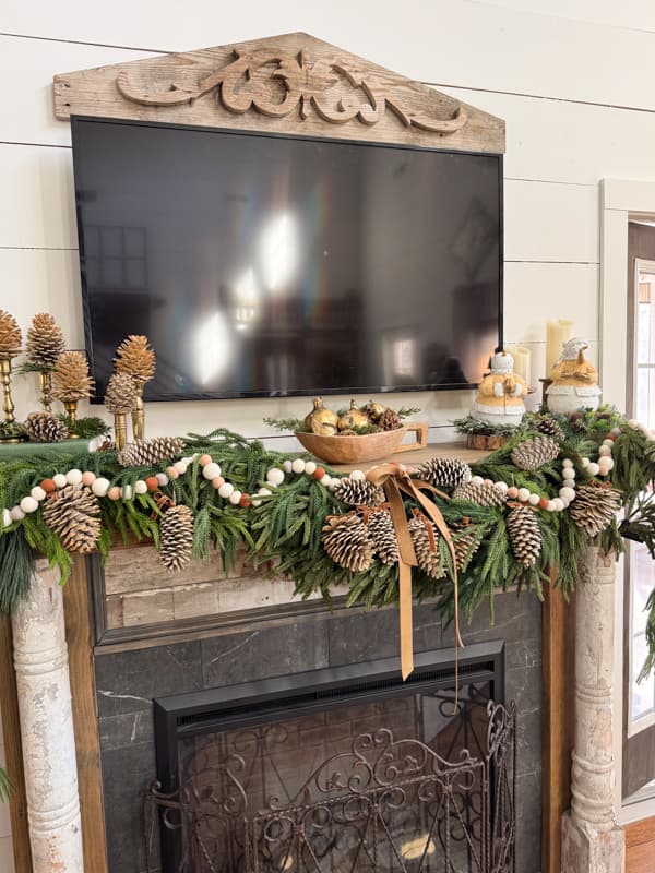 Winter mantel with greenery felt ball garland and bleached pinecones
