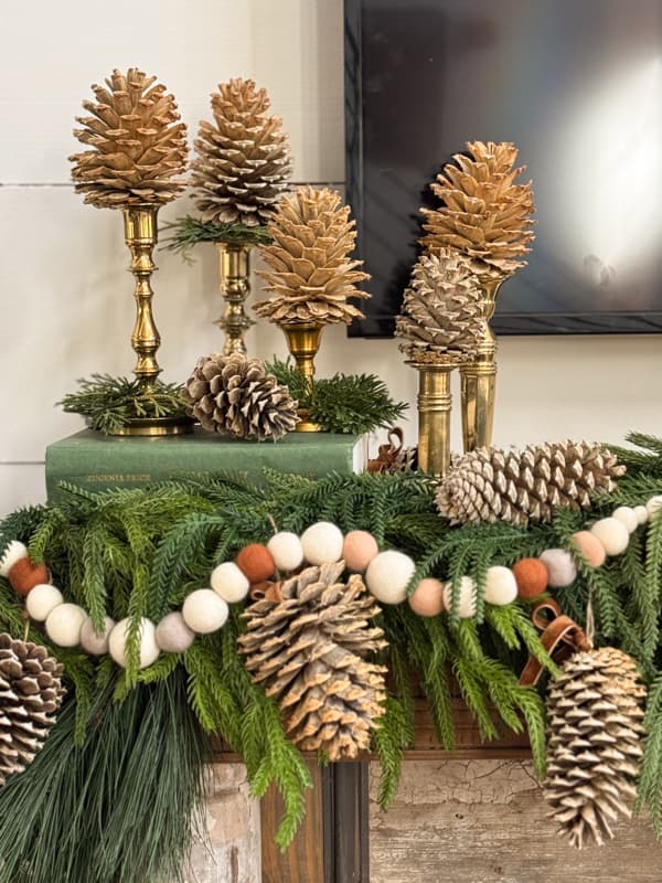 Winter Mantel with vintage brass candlesticks holding bleached pinecones with DIY felt ball garland