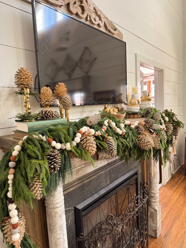 Winter Mantel With felt ball garland on greenery & bleached pinecones