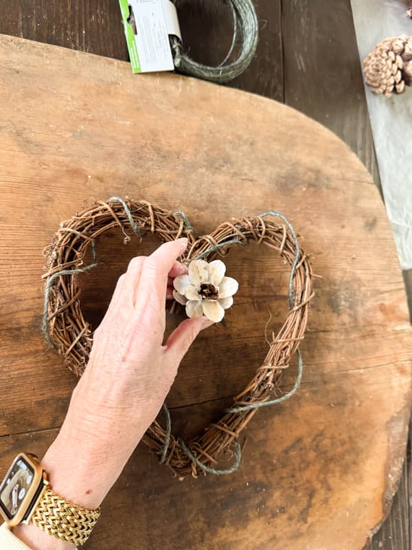 adhere the pinecone flower to the heart shaped grapevine wreath with. hot glue