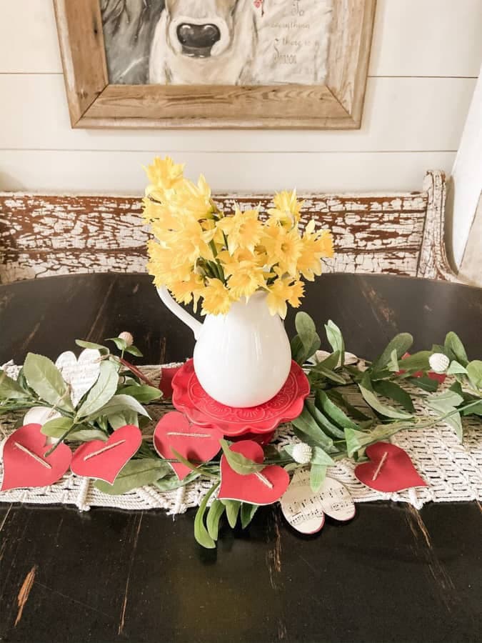 fresh daffodils in ironstone pitcher on red cake stand with DIY heart garland
