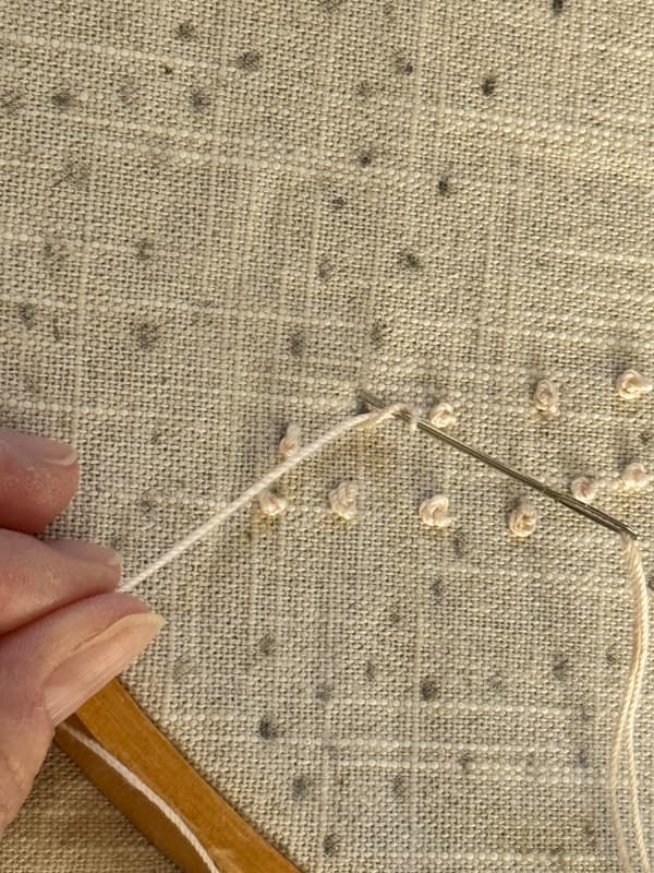 Hold thread taut & insert needle back into fabric for candlewick stitch