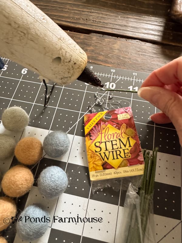 add tiny drop of hot glue to tip end of floral wire stem