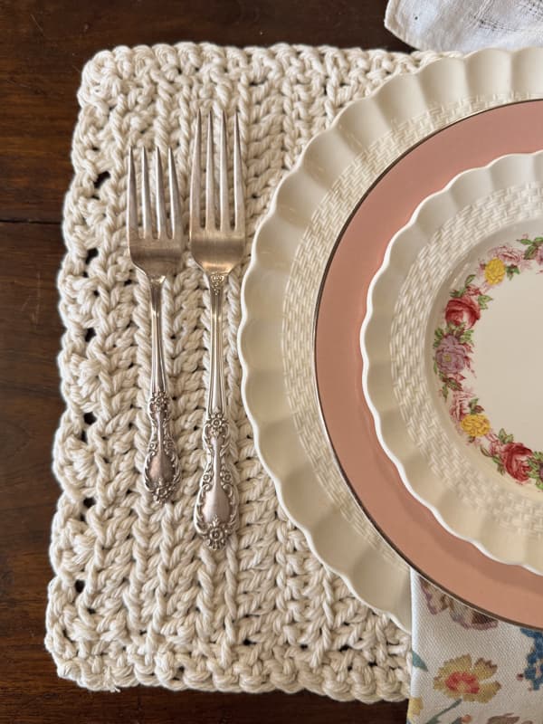 close up of crochet placemat with silverware and dishes