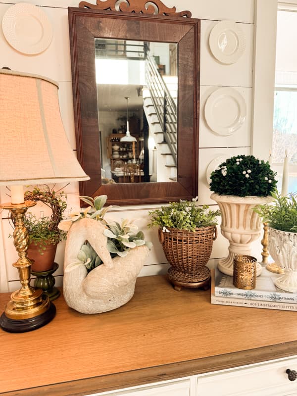 Spring Vignette with thrifted decor - swan planter, wicker planter, urn, mirror and plate wall