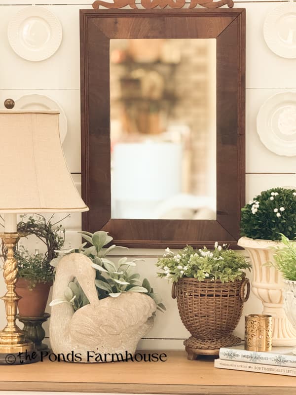 Spring Vignette with swan planter, lamp, mirror, wicker planter and plate wall
