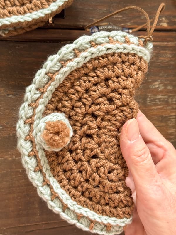 add oft crochet pom pon over the magnetic snap closure on DIY Crochet Eyeglass case