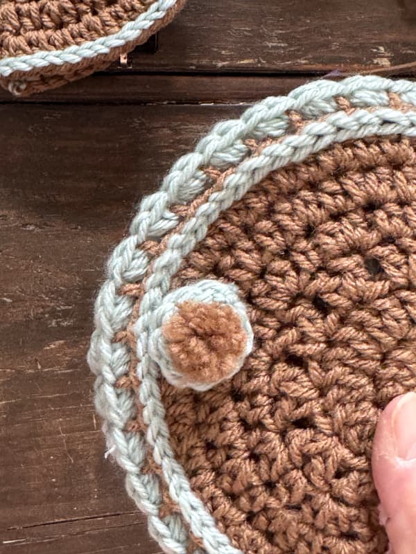 pom pom embellishment to cover the magnetic snaps on DIY Crochet Glass Case