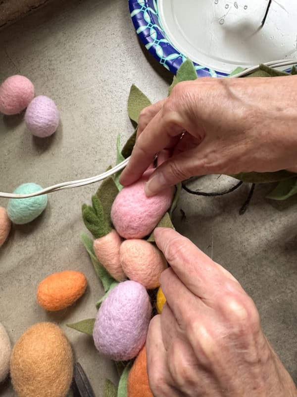 Add hot glue to the felt eggs to secure to the wreath and press until the glue sets