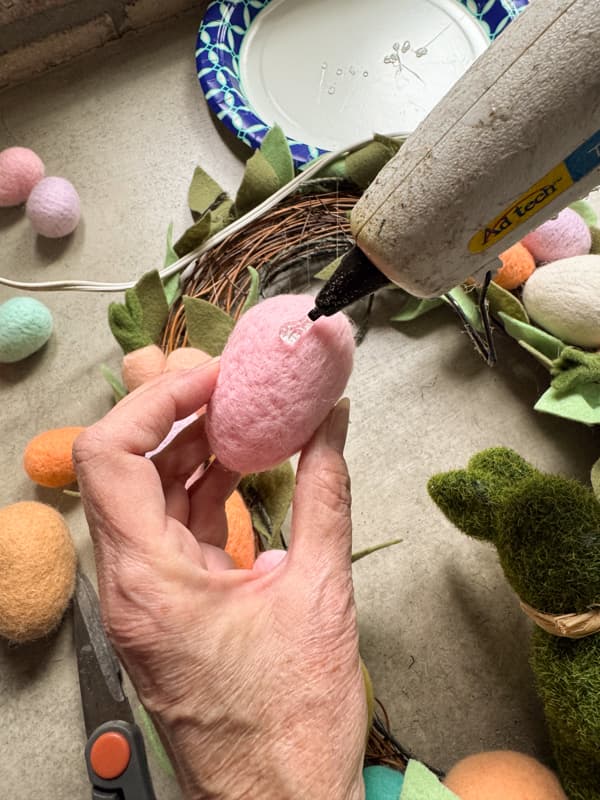 Add hot glue to the felt eggs to secure to the wreath