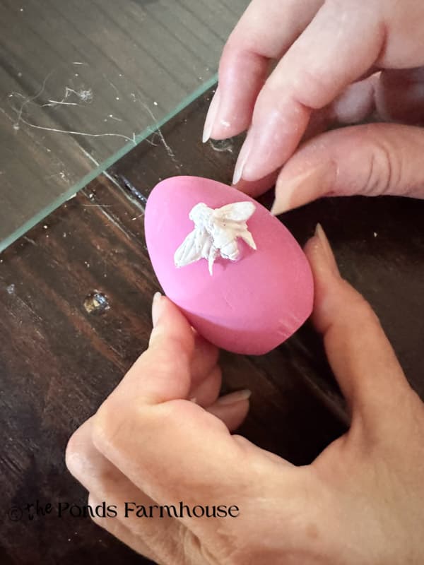 adding bee to wooden ;ink egg - DIY boutique style Easter Eggs with Hot Glue Bug Motifs