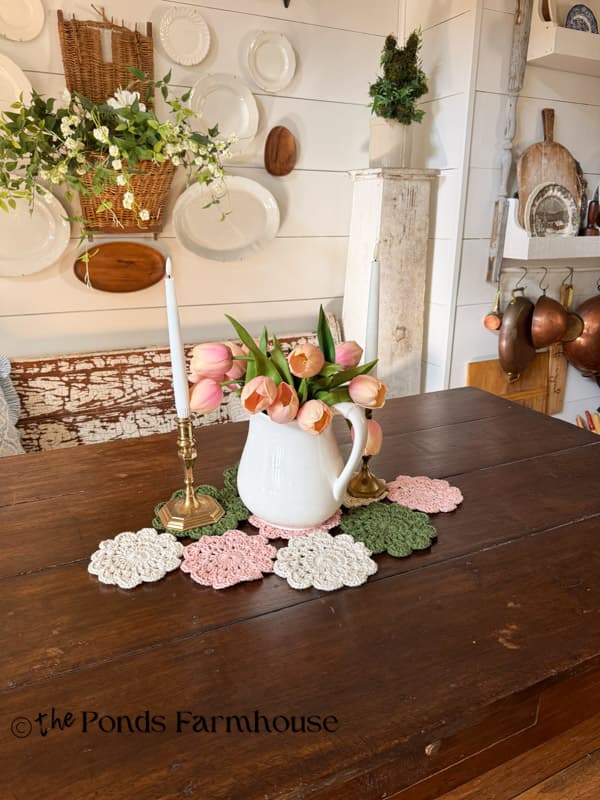 hand crochet doily table runner on rustic farmhouse table with pitcher, tulips and candlesticks