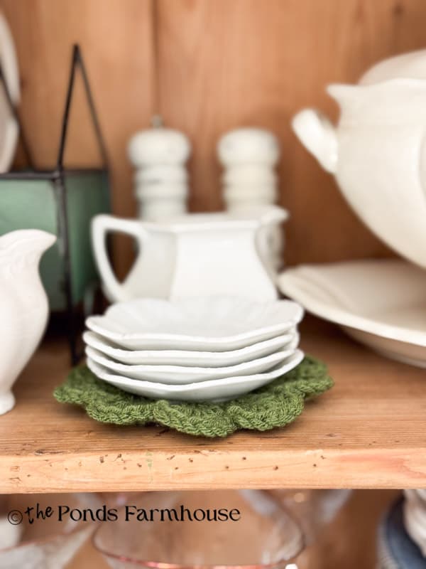 Green Crochet Doily with stack of ironstone butter pats