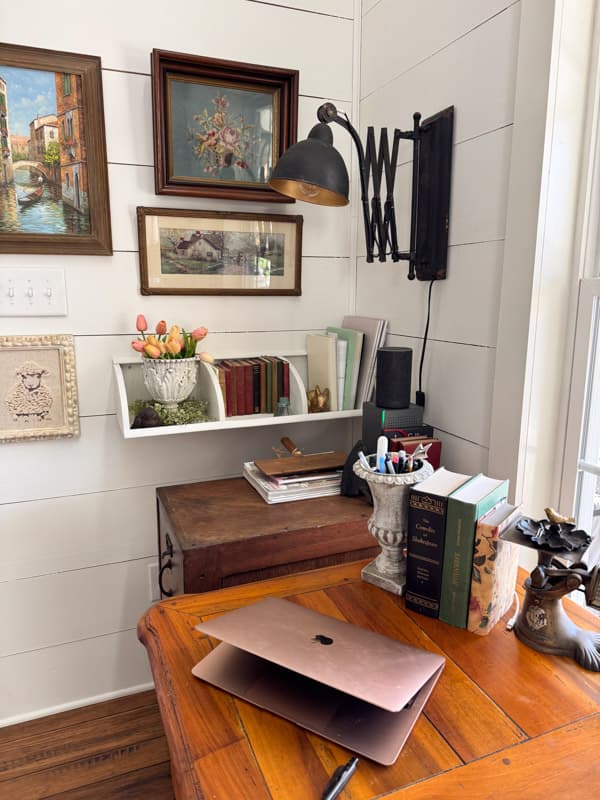 home office corner with wall shelf and gallery wall of vintage art